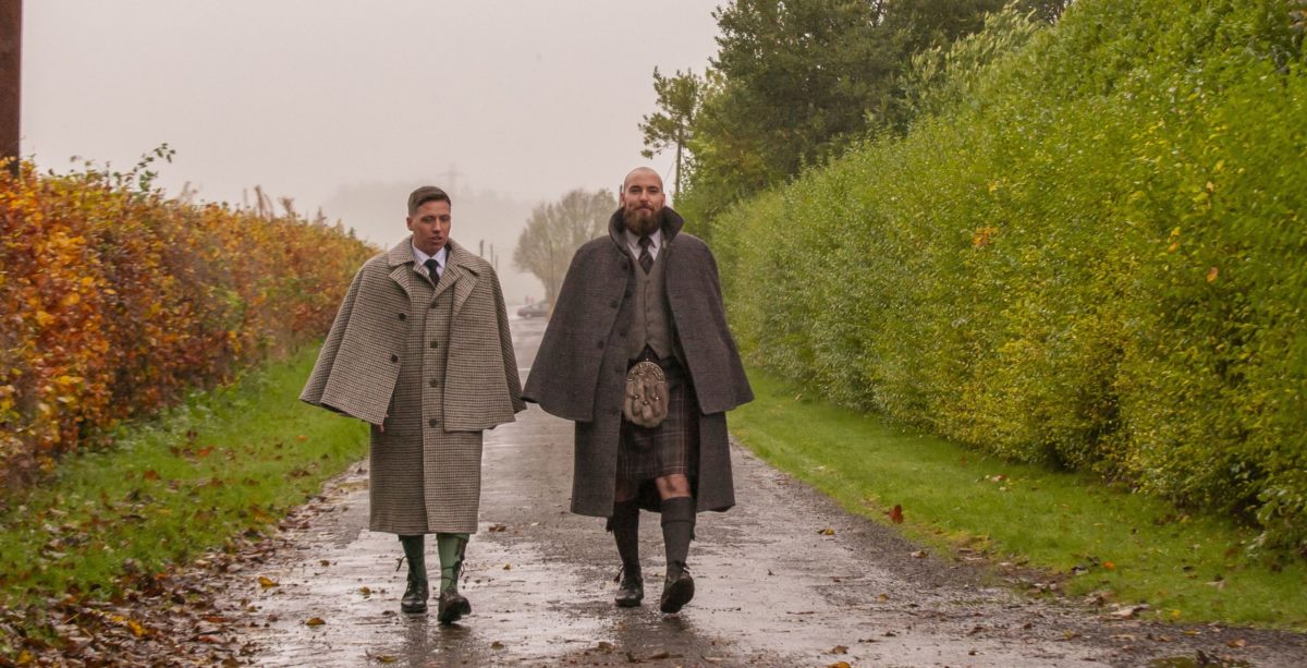 2 people in tweed capes walking in a path